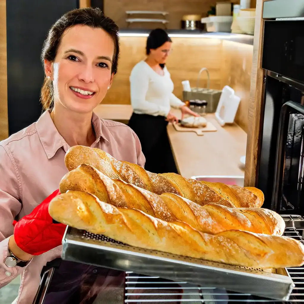 Michaela mit frischen Baguettes auf dem Blech in der Hand